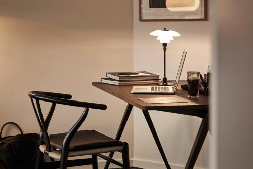a desk with a laptop and a lamp and a chair at Comwell Kongebrogaarden in Middelfart
