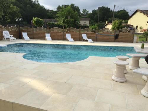 - une piscine avec des chaises blanches, une table et des chaises dans l'établissement Lake Les Landes, à Montpon-Ménestérol