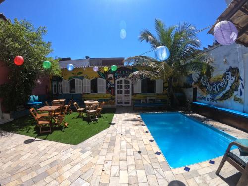 um quintal com uma piscina, uma mesa e cadeiras em Acquarela Hostel em Arraial do Cabo