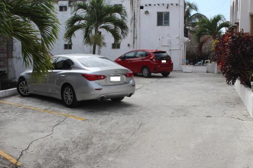 two cars parked in a parking lot with palm trees at Hotel Villas del Rey in Chachalacas