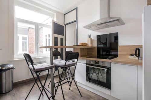 une cuisine avec deux tabourets de bar et un comptoir dans l'établissement Cosy appartement proche Gares, à Lille