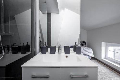 een witte badkamer met een wastafel en een douche bij Cosy appartement proche Gares in Lille