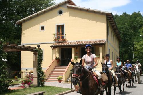 a group of people riding horses in front of a house at Hotel Relais Valle Orientina in Pitigliano