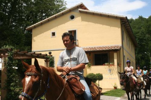 a man riding a horse in front of a house at Hotel Relais Valle Orientina in Pitigliano
