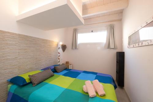 1 dormitorio con 1 cama colorida y toallas. en Happy House, en Viareggio