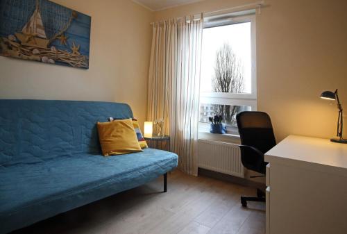 a living room with a blue couch and a window at Sea Haven - Morska Przystań in Jelitkowo