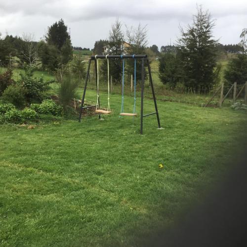 an empty swing set in a field of grass at Cabañas 4 Volcanes Frutillar in Frutillar