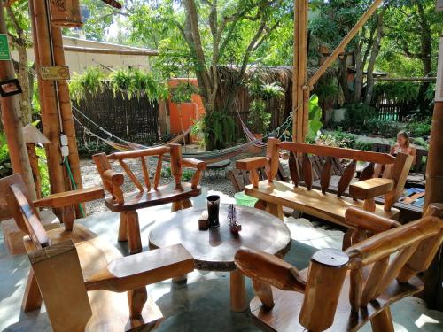 a group of wooden chairs and a table and a hammock at La Natura Hostel & Pool in Palomino