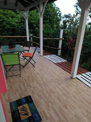 a porch with a table and chairs on a deck at Grenadier in La Trinité