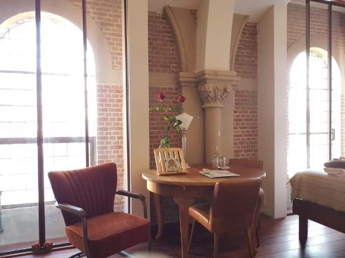 a room with a table and a chair and windows at SintAnna B&B PetitHotel in Yerseke