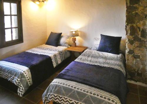two beds in a room with blue and white sheets at Finca Felix Appartement met Private Pool! in Lajares