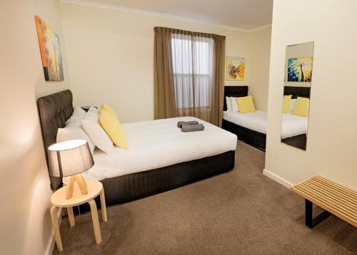 a hotel room with two beds and a mirror at Port Lincoln Foreshore Apartments in Port Lincoln