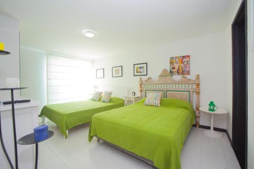 a bedroom with two beds with green sheets at Caribbean Loft Apartment in San Andrés