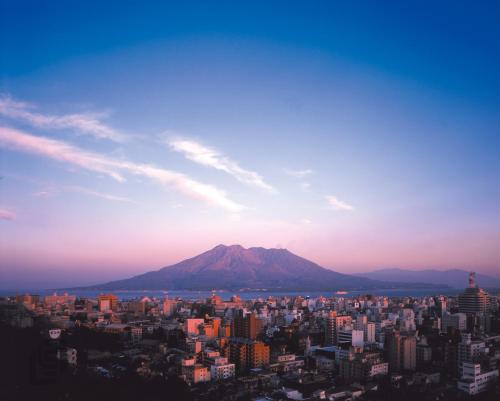 a view of a city with a mountain in the background at SHIROYAMA HOTEL kagoshima in Kagoshima