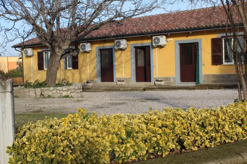 una casa amarilla con puertas rojas y un árbol en Le Casette in Collina en Cerveteri