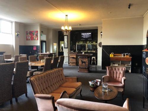 a restaurant with chairs and tables and a bar at Putaruru Hotel in Putaruru