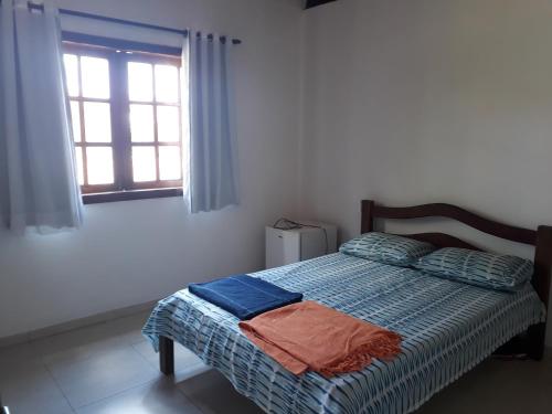 a bed in a room with a window and a bedspread at Casa Rústica em Gravatá in Gravatá