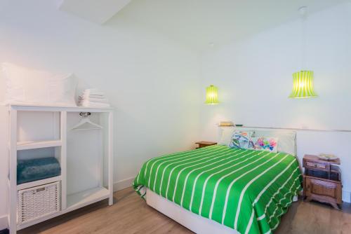 a bedroom with a bed with a green and white striped sheets at Casa Bonecos Rebeldes in Lisbon