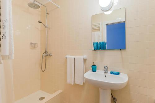 een badkamer met een wastafel, een douche en een spiegel bij Casa Bonecos Rebeldes in Lissabon