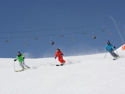 three people skiing down a snow covered ski lift at Ferienwohnung Kirschner in Fügenberg