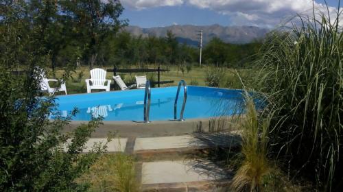 una piscina con 2 sillas blancas en un campo en Las Quimeras en Nono