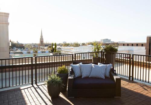 a couch on a balcony with a view of a city at The Restoration Hotel in Charleston