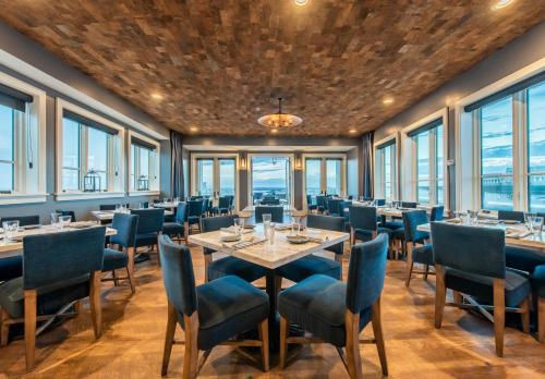 a dining room with tables and chairs and windows at The Restoration Hotel in Charleston