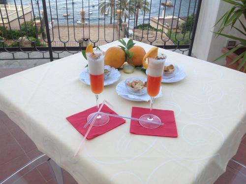 a white table with two glasses of juice and food at Hotel Baia Azzurra in Taormina