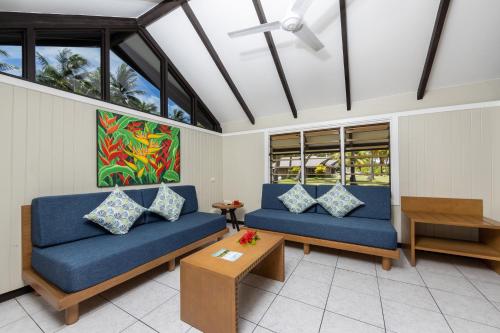 a living room with two blue couches and a table at Plantation Island Resort in Malolo Lailai