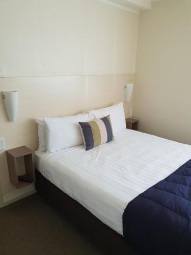 a bedroom with a large white bed with two pillows at Hananui Lodge and Apartments in Russell