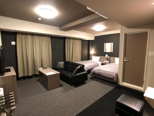 Habitación de hotel con cama y sofá en Hotel Route-Inn Koga Ekimae, en Koga