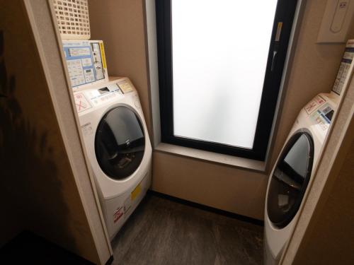 a laundry room with a washing machine and a window at Hotel Route-Inn Koga Ekimae in Koga