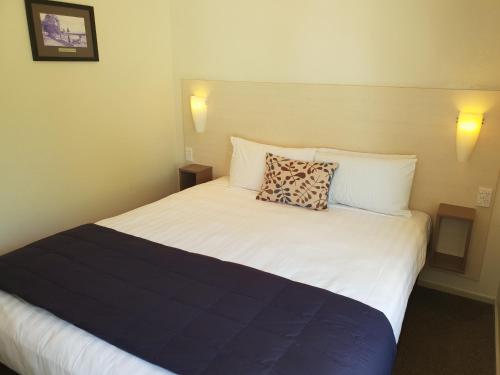 a bed in a hotel room with a pillow on it at Hananui Lodge and Apartments in Russell
