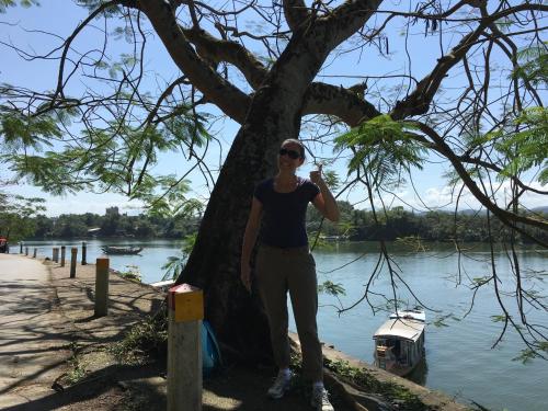 a woman standing next to a tree next to a river at Maily Hostel in Hue