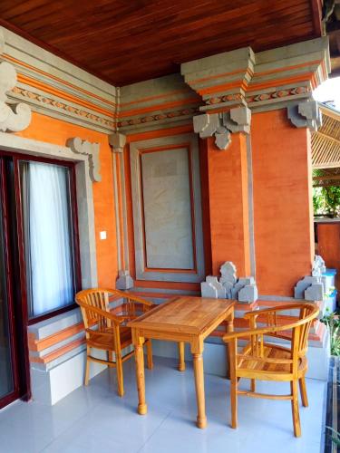a wooden table and chairs on the porch of a house at D'JERO HomeStay in Ubud