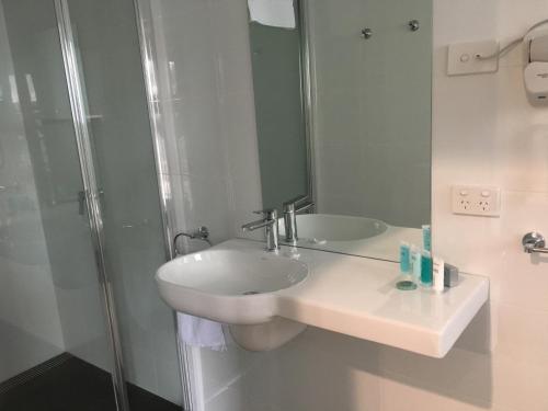a white bathroom with a sink and a shower at Tamar House in Rosevears