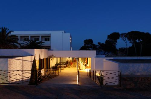 a white building with a walkway at night at Hostal Empúries in L'Escala
