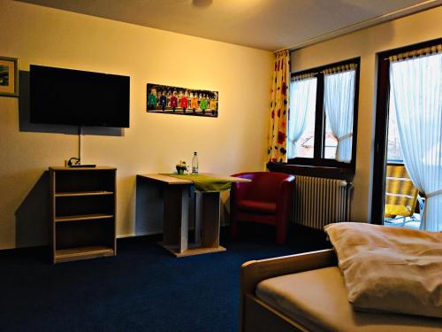 a hotel room with a couch and a television at Das Gästehaus Eimeldingen in Eimeldingen