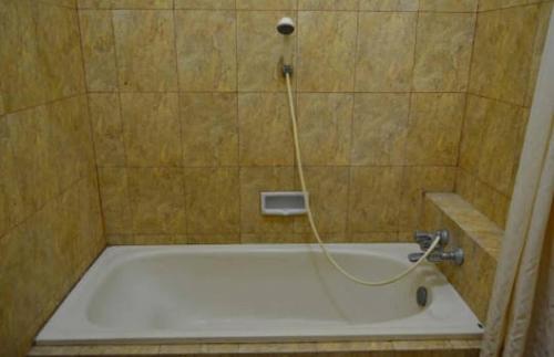 a bath tub with a hose in a bathroom at Hotel Tiger in Yogyakarta