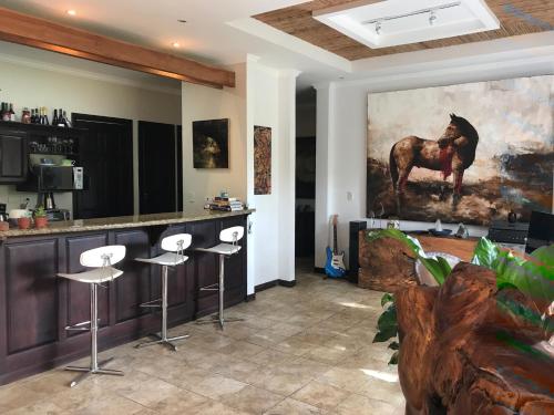 a bar with stools and a painting of a horse at Palm Coast Luxury Rentals in Esterillos Este