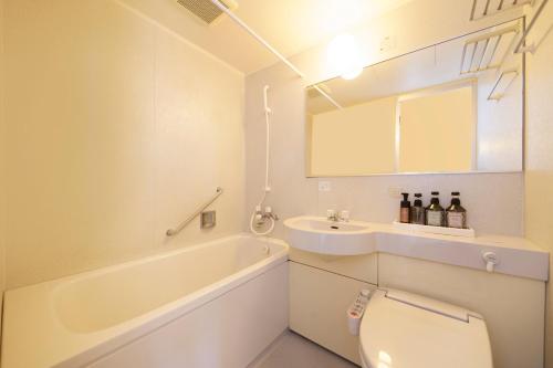 a bathroom with a tub and a toilet and a sink at Quintessa Hotel Iseshima in Shima