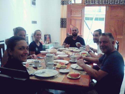 a group of people sitting around a wooden table at Daffodils Inn in Adams Peak
