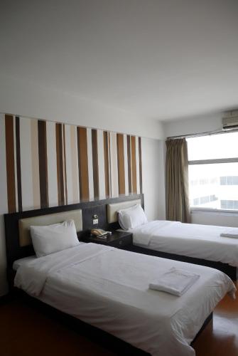 a hotel room with two beds and a window at Roma Hotel in Khon Kaen