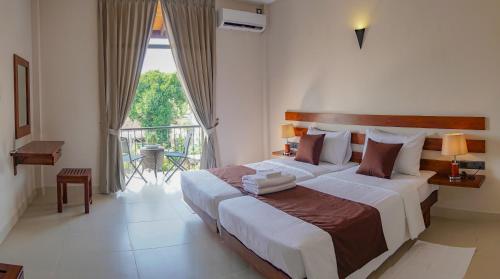a bedroom with a large bed and a balcony at Hive 68 - Hotel and Resorts (Negombo) in Negombo