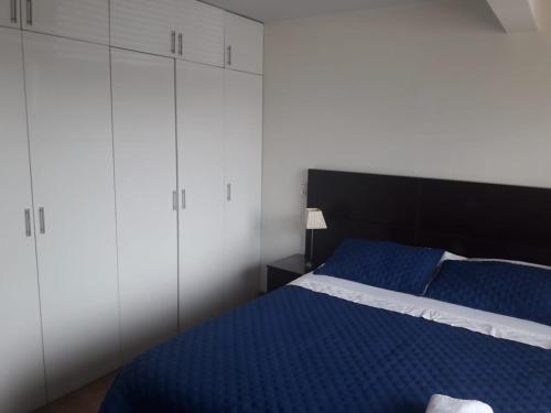 1 dormitorio con 1 cama azul y armarios blancos en Departamento en Chacarilla, San Borja, en Lima