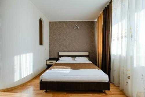 トムスクにあるApart Petrovskie at Bazarnykh 12のベッドルーム1室(白いシーツとカーテン付きのベッド1台付)