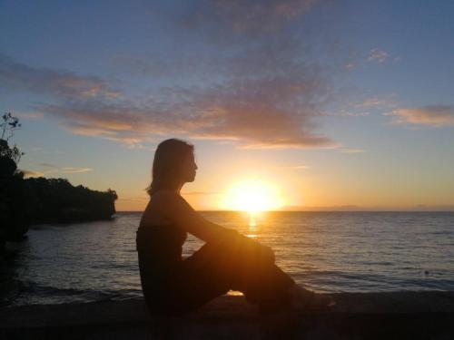a woman sitting on the beach watching the sunset at Jelly Sea Resort in Siquijor