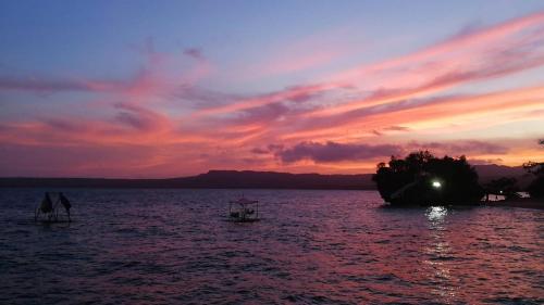 a boat in a body of water with a sunset at Jelly Sea Resort in Siquijor