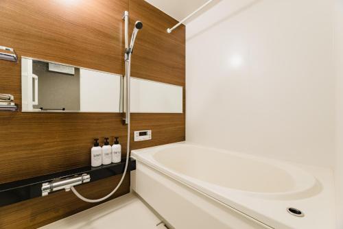 GRAND BASE Fukuoka في فوكوكا: حمام مع حوض أبيض ومغسلة
