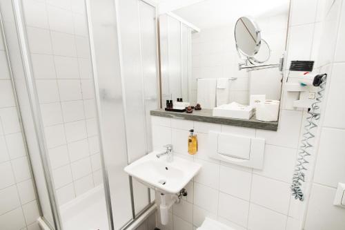 a white bathroom with a sink and a mirror at Sorell Hotel Rex in Zürich